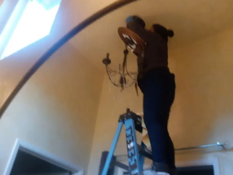 Electrician installing a chandelier in a Hillsdale residence